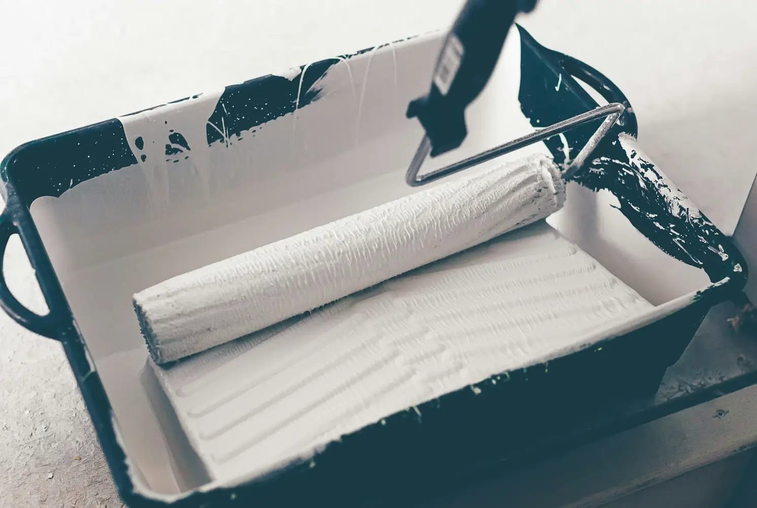 Un rouleau de peinture dans son bac, prêt à peindre un mur. Il représente le coup de peinture à donner à votre application pour la maintenir.