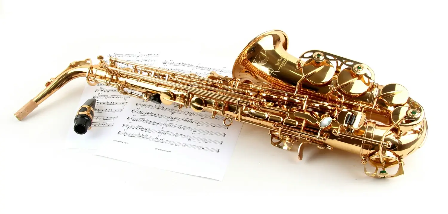 Un saxophone couché sur une partition de musique. Dans la musique, la maintenance des outils permet des notes justes.